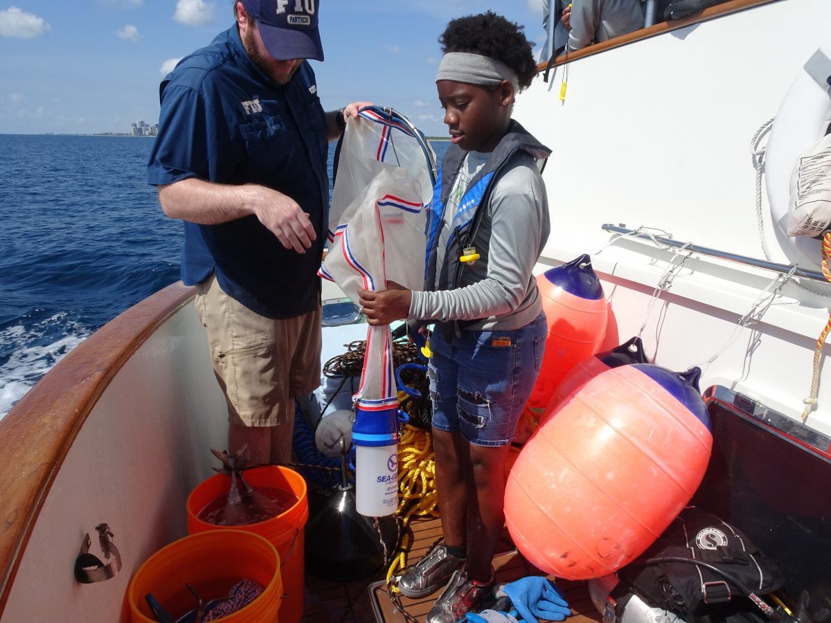 EXP 27: A student helps Nick with the plankton net and sample bottle; PC: Rachel Plunkett
